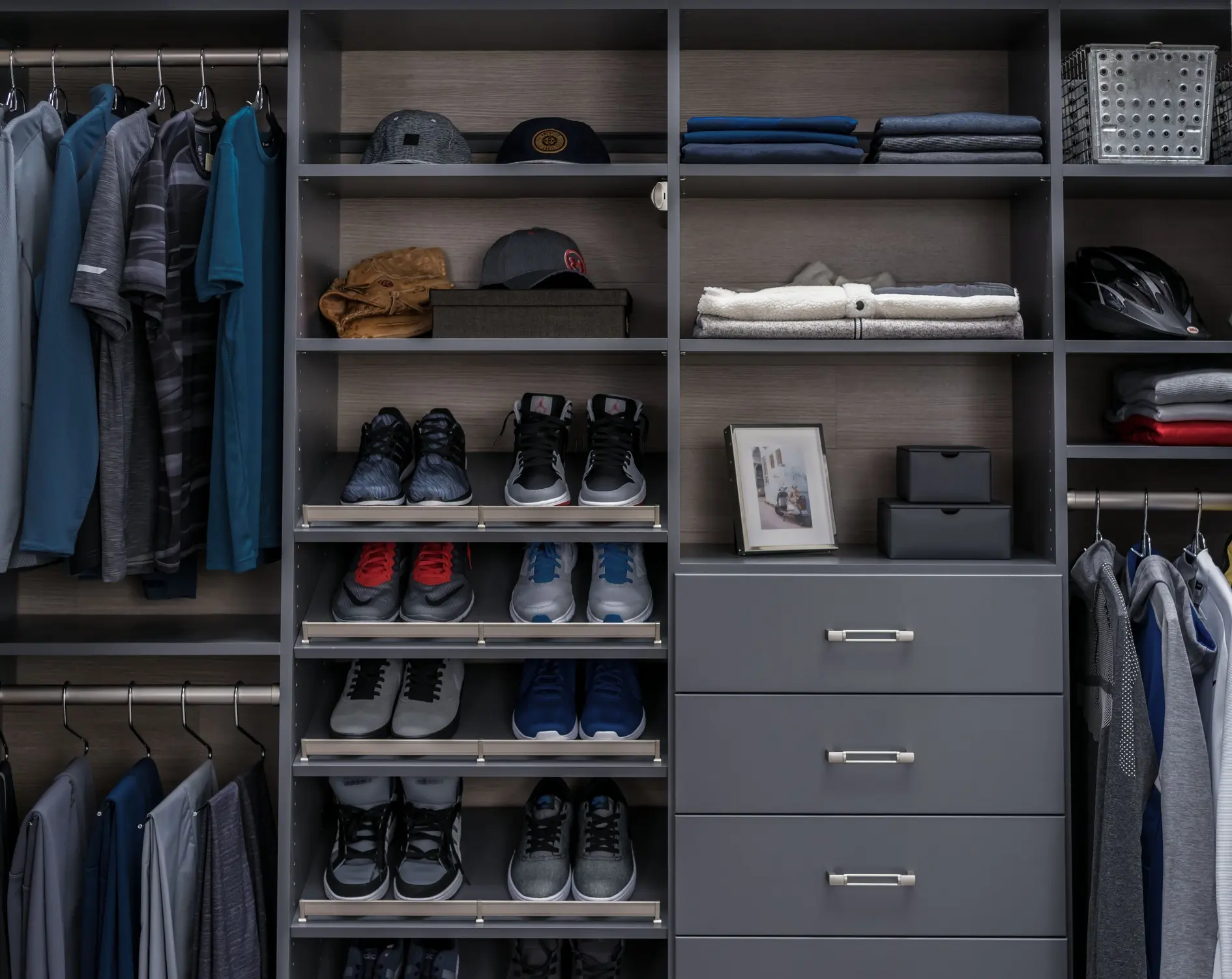 Dark grey wood-grain custom closet with pull-out shoe shelves in a Rehoboth Beach, Delaware vacation home